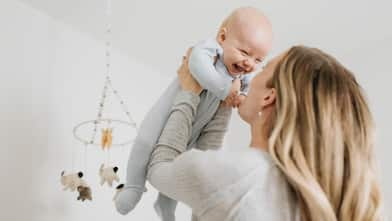 Mother throwing baby boy in air in bedroom