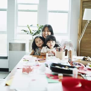 Mother and two small daughters sitting at table in craft room