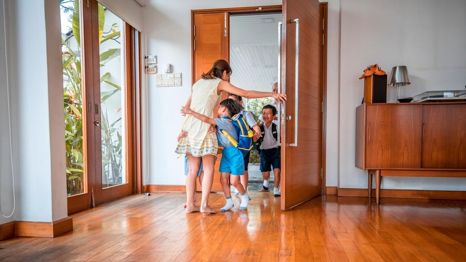 A mother embracing her children at the front door