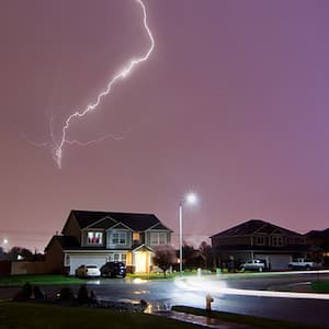 A lightning during a storm strikes above a house