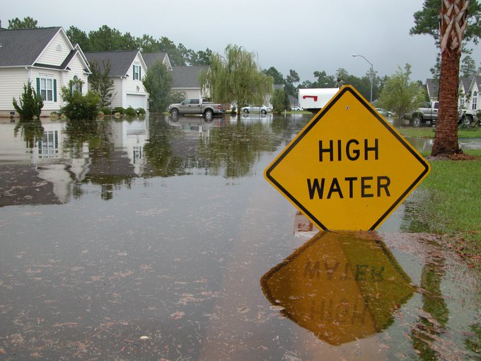 Flooded road with yellow sign that says "High Water"