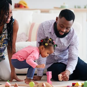 Parents playing with their toddler and a wooden railway