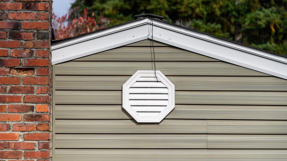 The exterior wall of a house with an attic fan