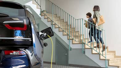 A mother and child in a garage with an electric car