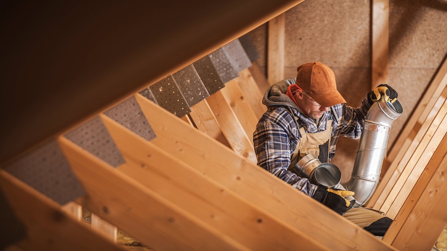 Technician repairing a house’s ventilation in an attic