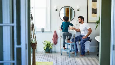 Father helping son brushing teeth in the bathroom