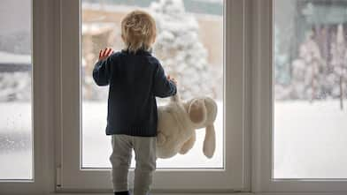 Child looks out door at winter scene