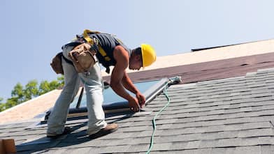 An roofer installing flashing on skylight