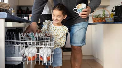 A father helping his daughter to load the dishwasher