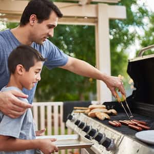 A father teaches his son how to grill