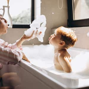 A mother bathes her son in a bathtub