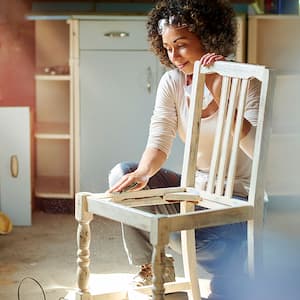 A woman repairs a wooden chair