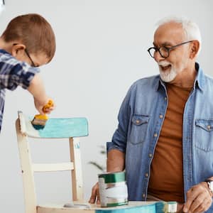 Grandfather and grandson painting a chair blue