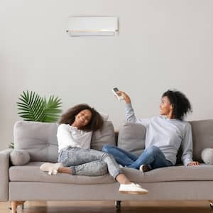 mother and daughter sit on couch in living room smiling and enjoying air conditioning