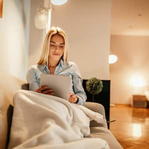 Woman reading comfortably under blanket