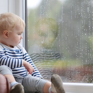 A baby watching rain out the window