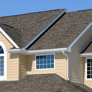 view of top of house with tan siding and gray shingles with multiple windows