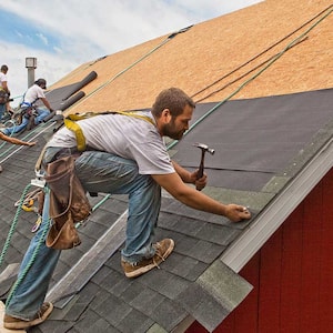 Group of workers installing new roof shingles