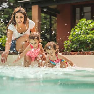 Mom and toddler daughters playing in the swimming pool