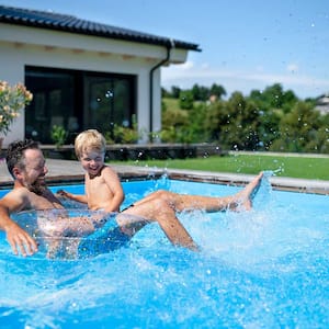 A father and son play in a swimming pool