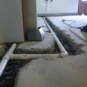 Pipe being installed in basement floor.