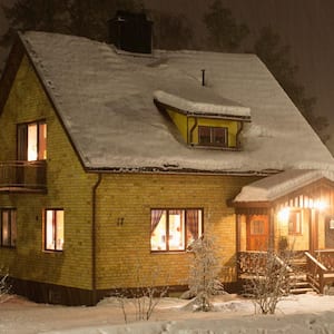 An illuminated house at night during winter covered in snow