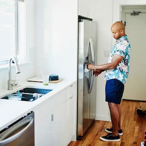 A man fills a pitcher at a refrigerator water dispenser
