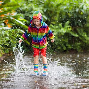 Child playing in a large puddle in the rain