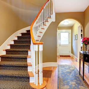 stairs and railing lead upstairs while hallway features arched doorway and entry way table