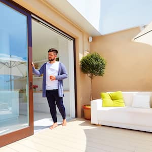 Man holding a drink is opening the patio sliding door 