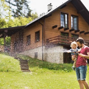 A little boy with his father watering the lawn