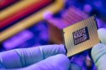 TWO GLOVED HANDS HOLD A SEMICONDUCTOR CHIP