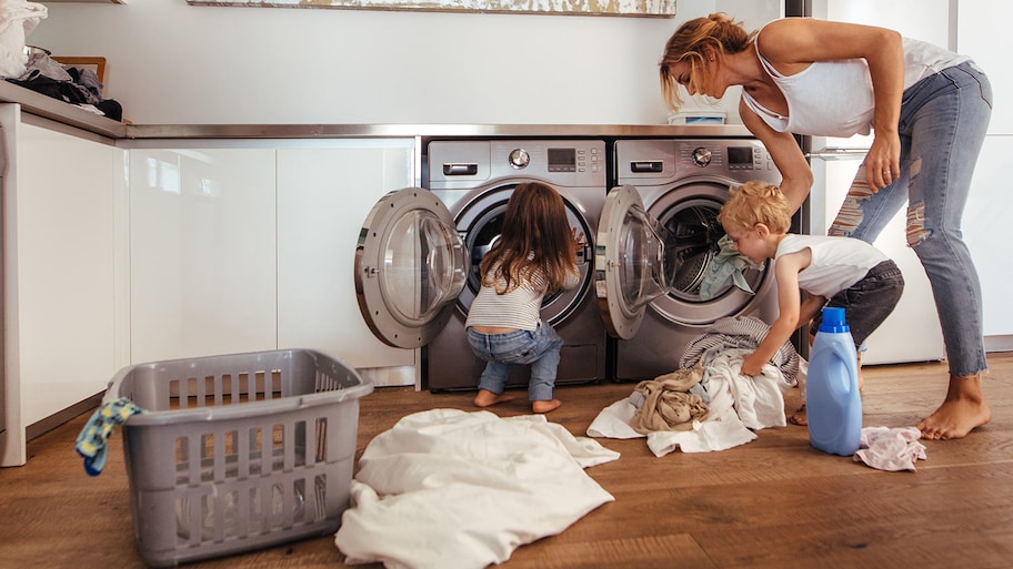 Two kids help mom with the laundry