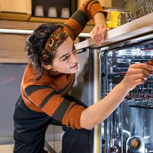 A woman installing a new dishwasher