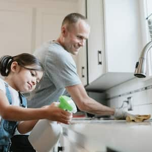 A father and his daughter cleaning their kitchen sink