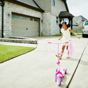 Girl playing with scooter on the driveway