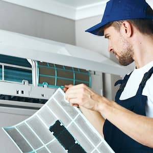 A professional replacing the air filter of an air conditioner