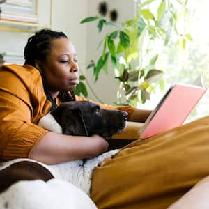 Woman reading book and snuggling with her dog