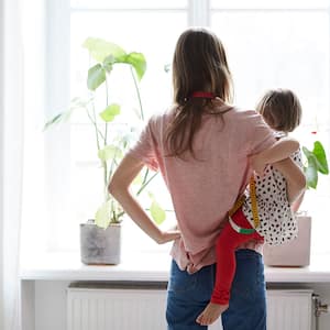 A woman and child stand in front of curtains with measuring tape