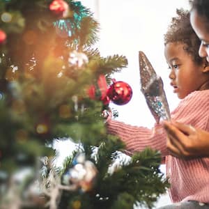 A mother and child decorate a Christmas tree