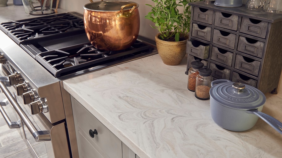 Light Corian kitchen counter around stove with copper pot