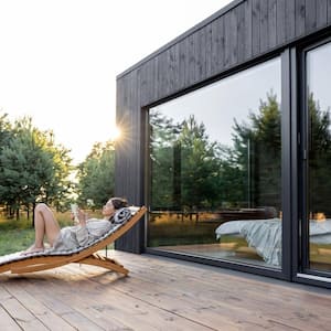 A woman resting on a terrace of a contemporary house next to pine trees