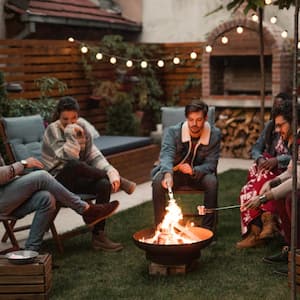 Friends hanging out by fire pit in backyard