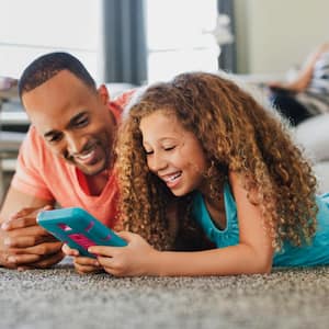 Father and daughter playing while lying on floor at home