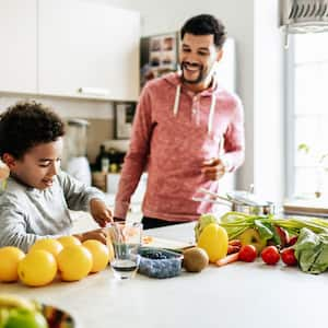 A boy and his father preparing juice in the kitchen