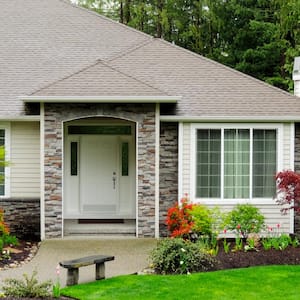 A modern home with green grass and trees in front yard