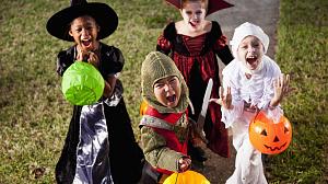 Four children wearing costumes with pumpkin trick or treat buckets in their hands.