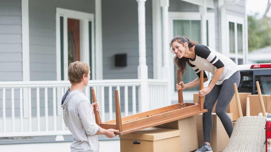 Couple moving furniture into new home