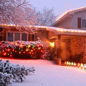 A beautiful snow covered house with various Christmas lights