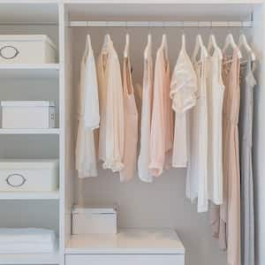 Tops and dresses hanging in a white closet